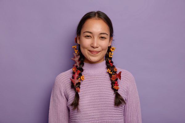 glad-natural-asian-woman-celebrates-fall-has-two-plaits-decorated-with-red-autumn-leaves-berries-flowers-wears-purple-sweater-isolated-violet-wall-october-time (1)